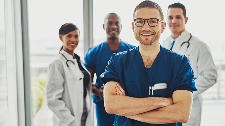 Image of one doctor standing out in front of three other doctors
