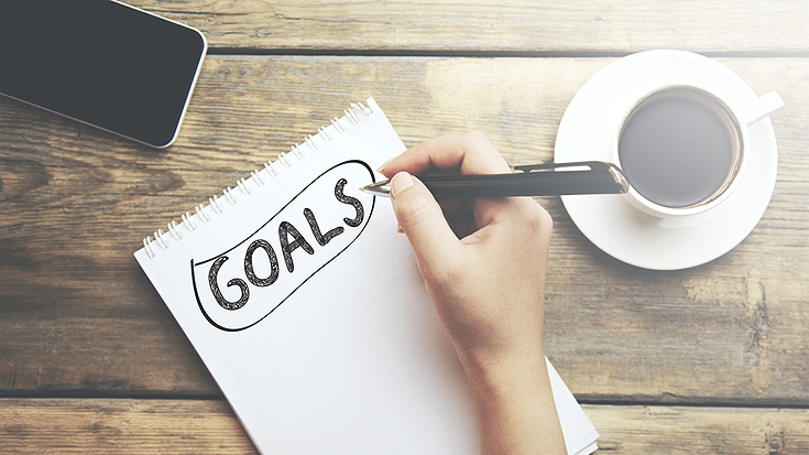 Image of woman writing "goals" on notebook