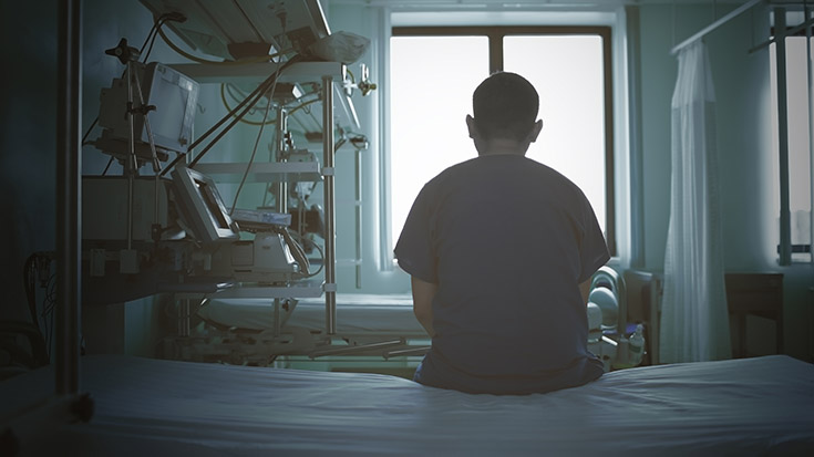 image of medical professional sitting on empty patient bed