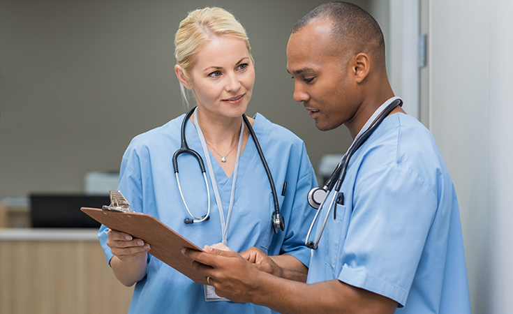 image of make and female medical professionals reviewing clipboard