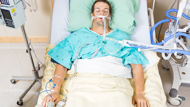 image of patient with breathing tube in hospital bed