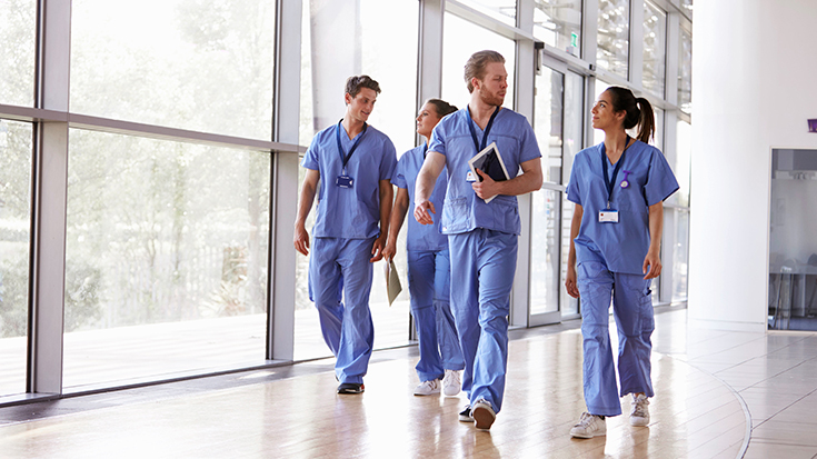 image of medical professionals walking down hallway, talking with each other