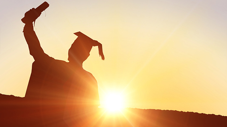 silohouette of graduate in cap and gown holding diploma