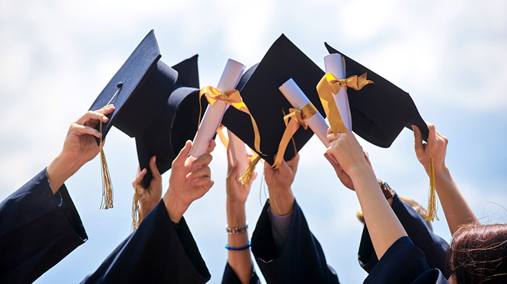 Image of graduates holding up caps and diplomas
