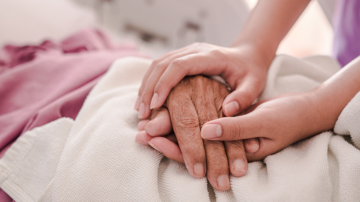 image of family member holding patient's hand while in hospital bed