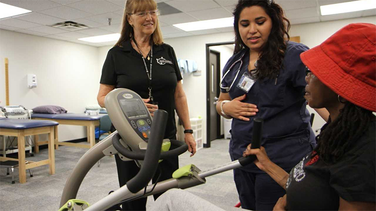 photo of respiratory therapists working with patient on stationary bike
