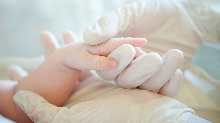 image of health care professional holding baby's hand