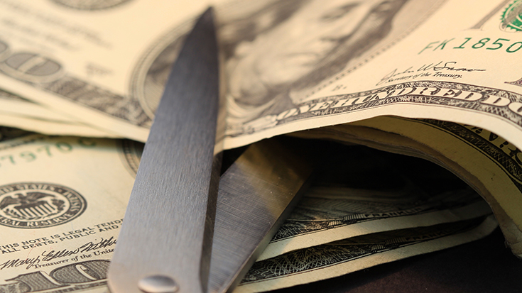 image of scissors attempting to cut paper money