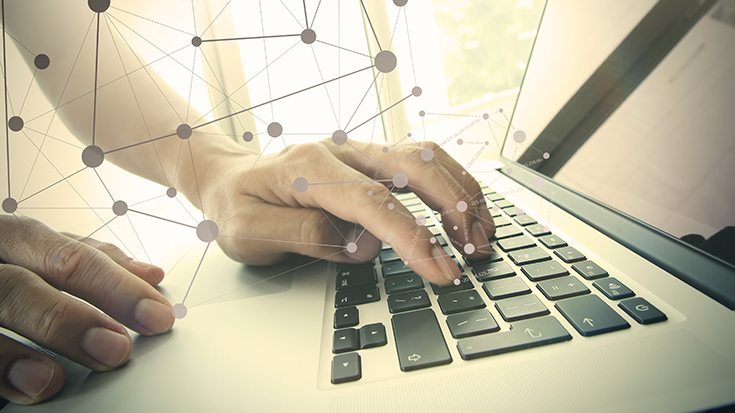 image of person typing on laptop with networking symbols in foreground