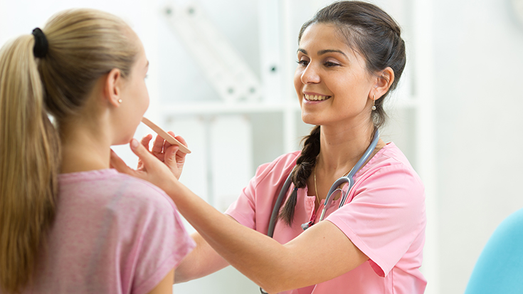 image of female health professional inspecting throat of young girl