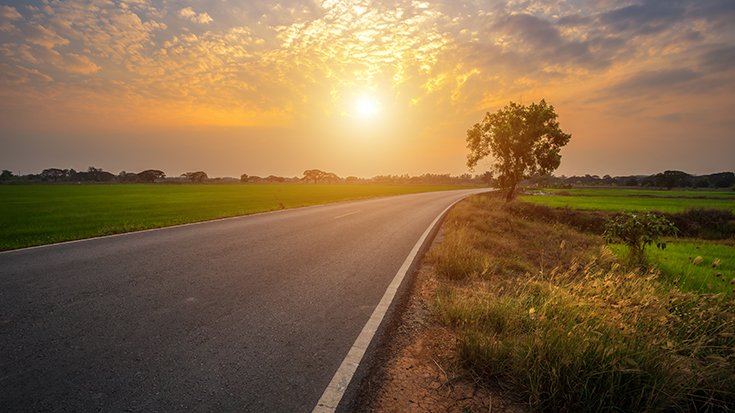 photo of sun setting on paved road in rural setting