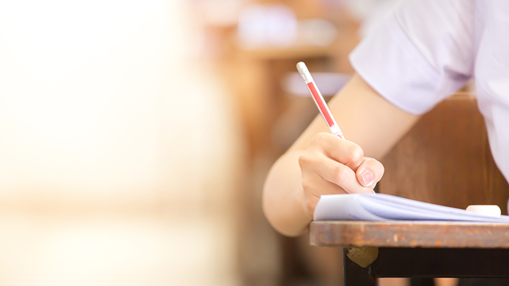 photo of a student writing on paper at a desk