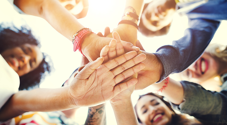 image of young adults reaching hands into center of circle