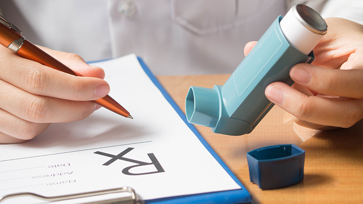 image of medical professional holding inhaler and writing prescription information