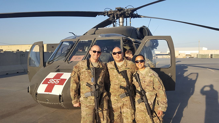 photo of military RT aaron hamblin with team members in front of a helicopter
