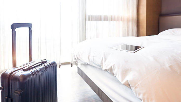 hotel room with suitcase and tablet
