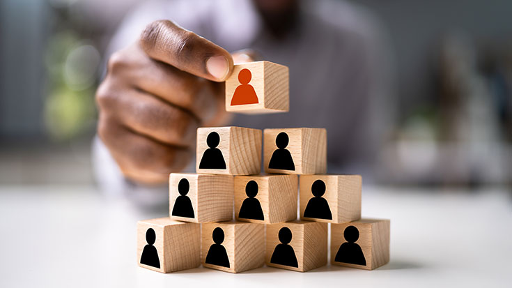 Image of man stacking wooden blocks with human silhouettes on them